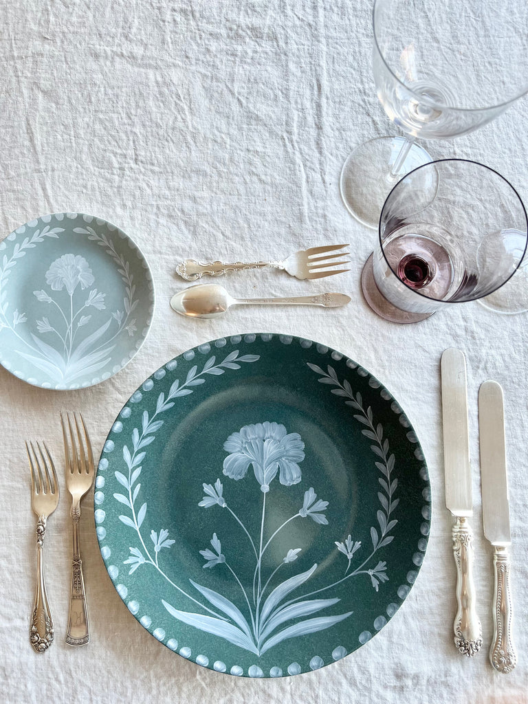 green dinner plate with hand painted white floral design in placesetting