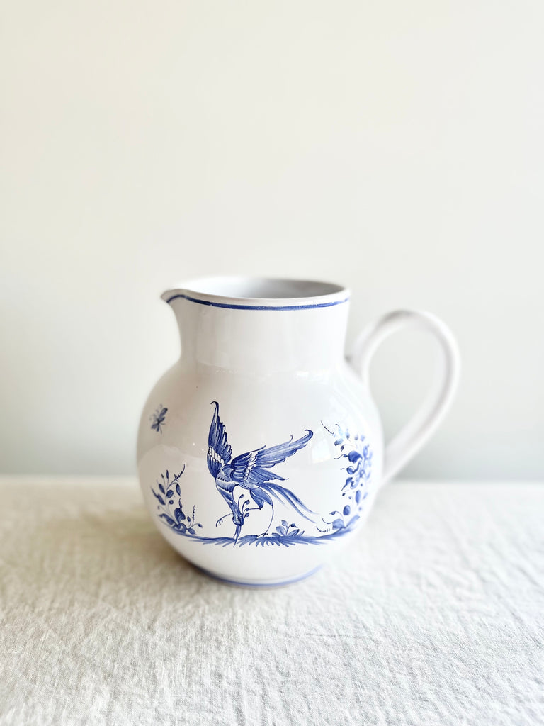 blue and white pitcher with blue phoenix design on white table