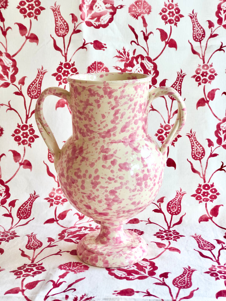cream amphora vase with pink speckle pattern 13 inches tall on red and white cloth