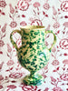 amphora vase in green and cream speckle pattern on red and white cloth