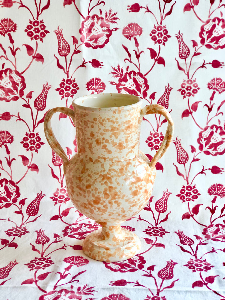 cream amphora vase with light brown speckle pattern 13 inches tall on red and white cloth
