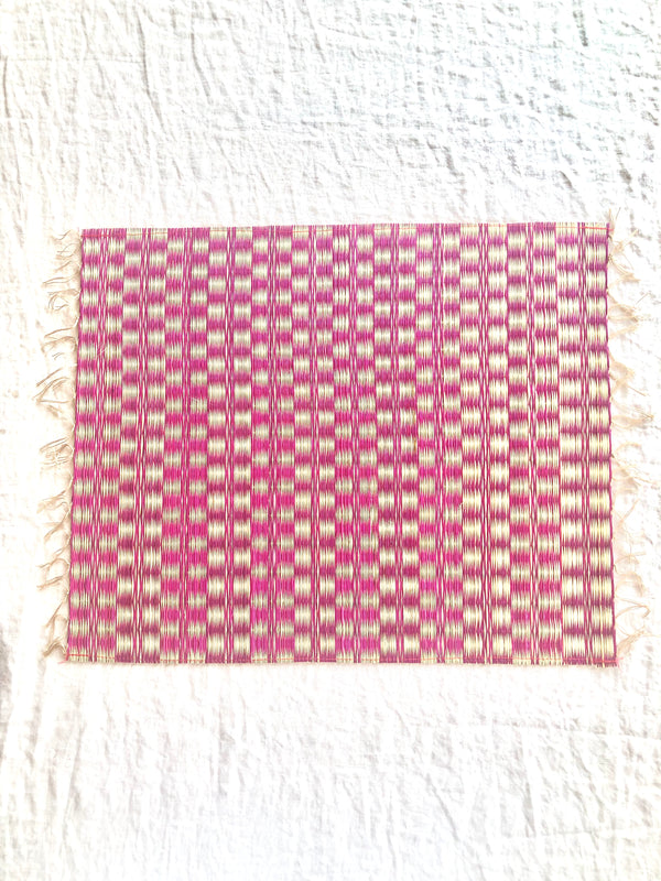 pink and white woven placemat with fringed ends