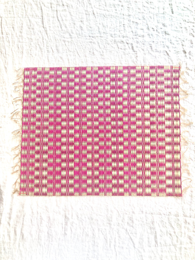 pink and white woven placemat with fringed ends