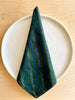 cotton napkin green with dark and light blue stripes folded over a plate