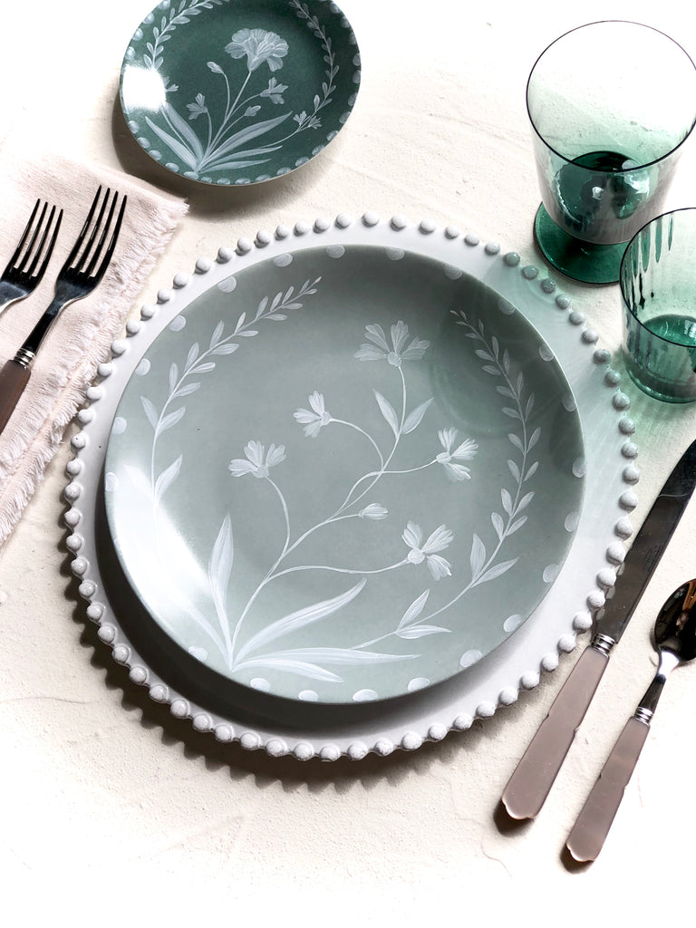 green bread plate with hand painted white floral design in place setting
