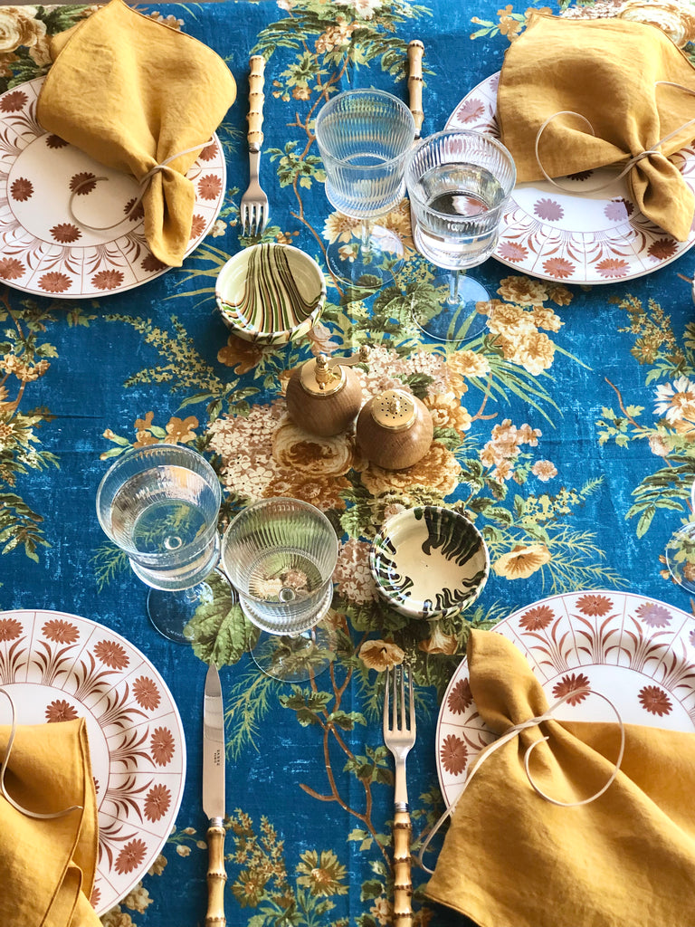 blue tablecloth with cream white and light brown floral pattern with placesetting