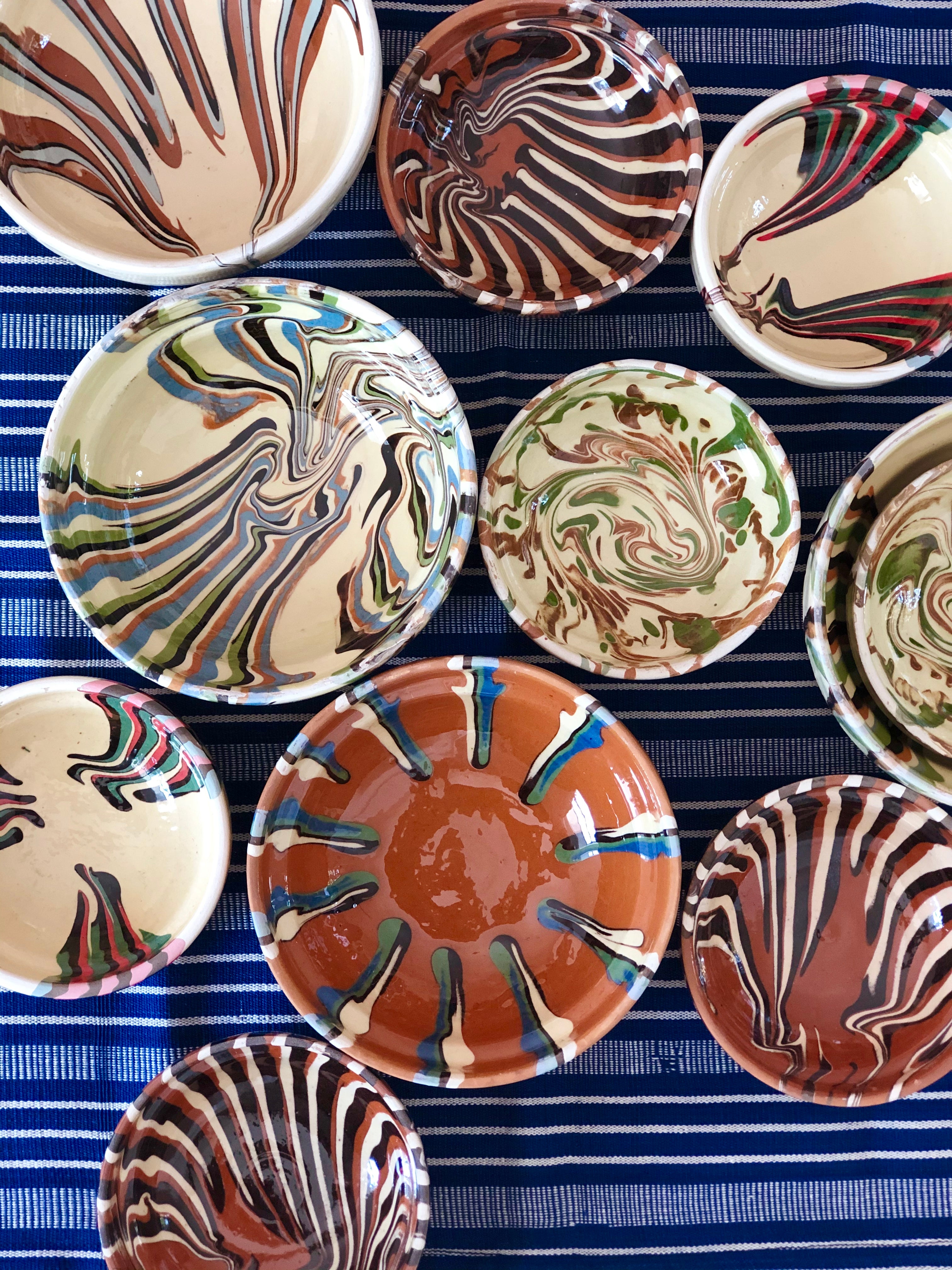 multicolor ceramic bowls group on white tablecloth 4 inches in diameter on blue striped cloth