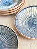 blue and white dinner plate with radial peacock pattern on table