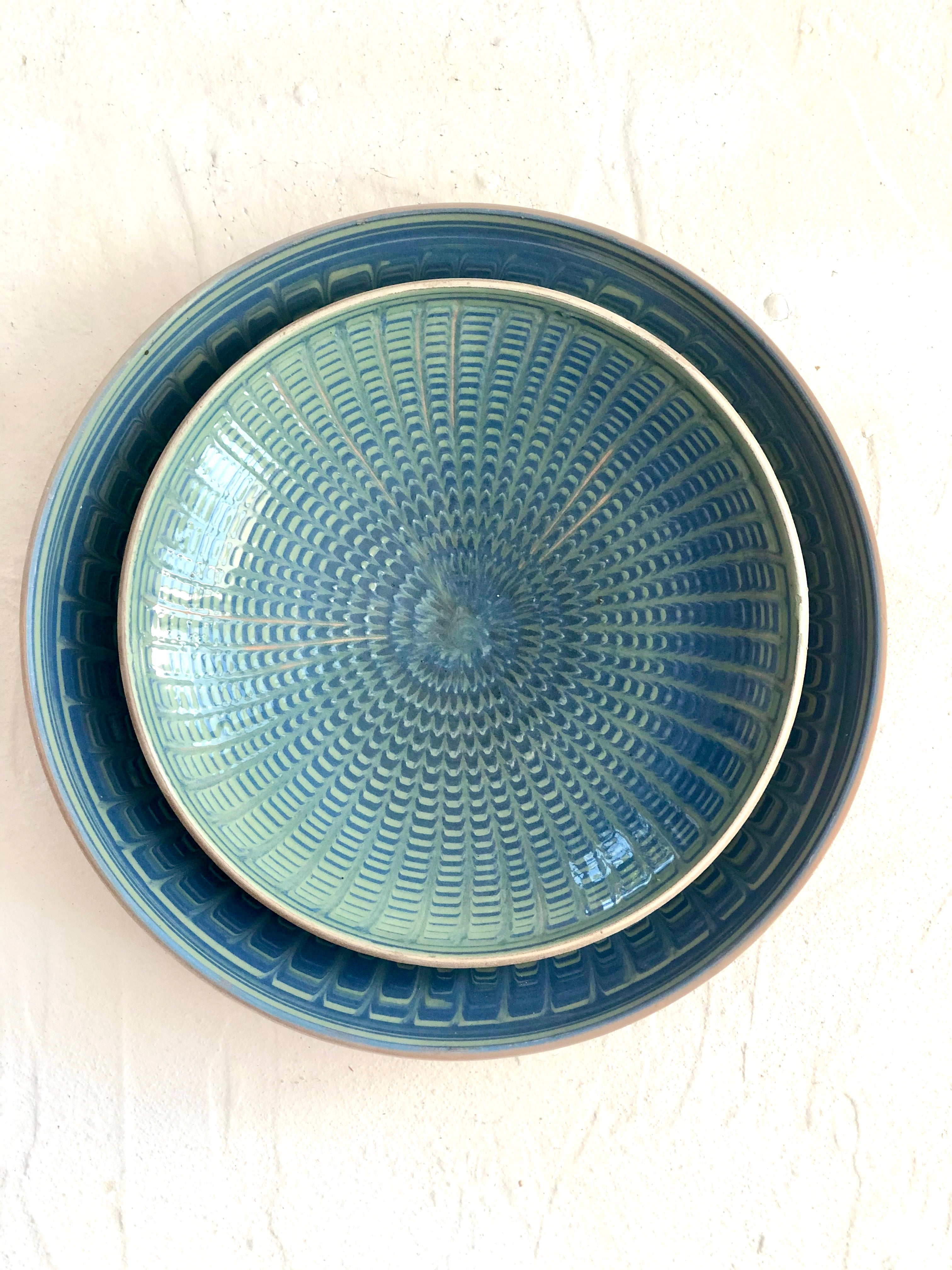 teal and green salad plate with radial peacock pattern with dinner plate