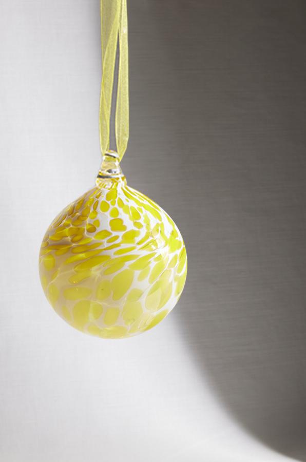 hand blown glass ornament with yellow and cream speckle pattern on white background