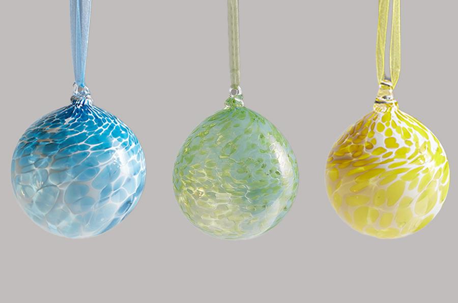 set of three hand blown glass ornaments in yellow green and blue hanging from ribbons