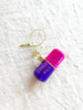 pink and purple glass christmas ornament shaped like a capsule with chill pill written on side detail view