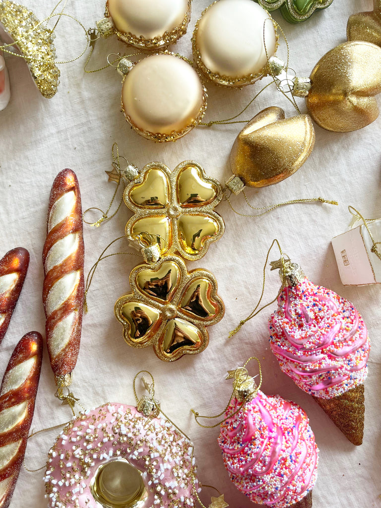 gold macaroon shaped christmas ornament on table with other ornaments