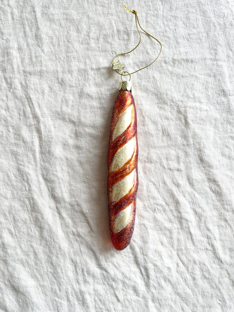 glass christmas ornament shaped like french baguette with gold ribbon