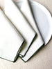 white rolled edge linen napkins with forest green edge 18 inch square folded on plate