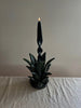 green taper candle holder shaped like the top of a pineapple with lit candle