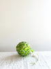 glass christmas ornament shaped like artichoke on linen tablecloth
