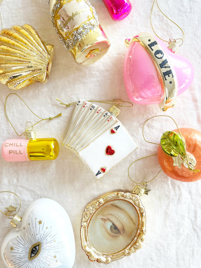pink and gold glass christmas ornament shaped like a capsule with chill pill written on side with other ornaments