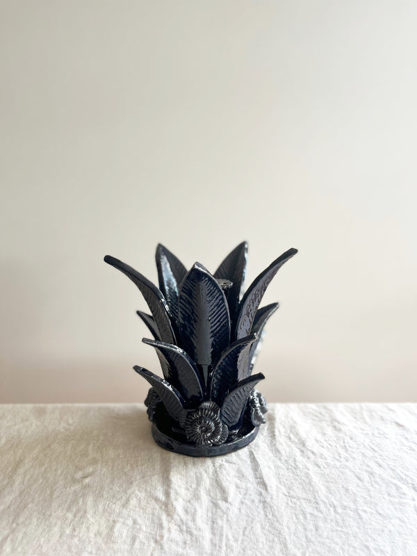 navy blue taper candle holder shaped like the top of a pineapple