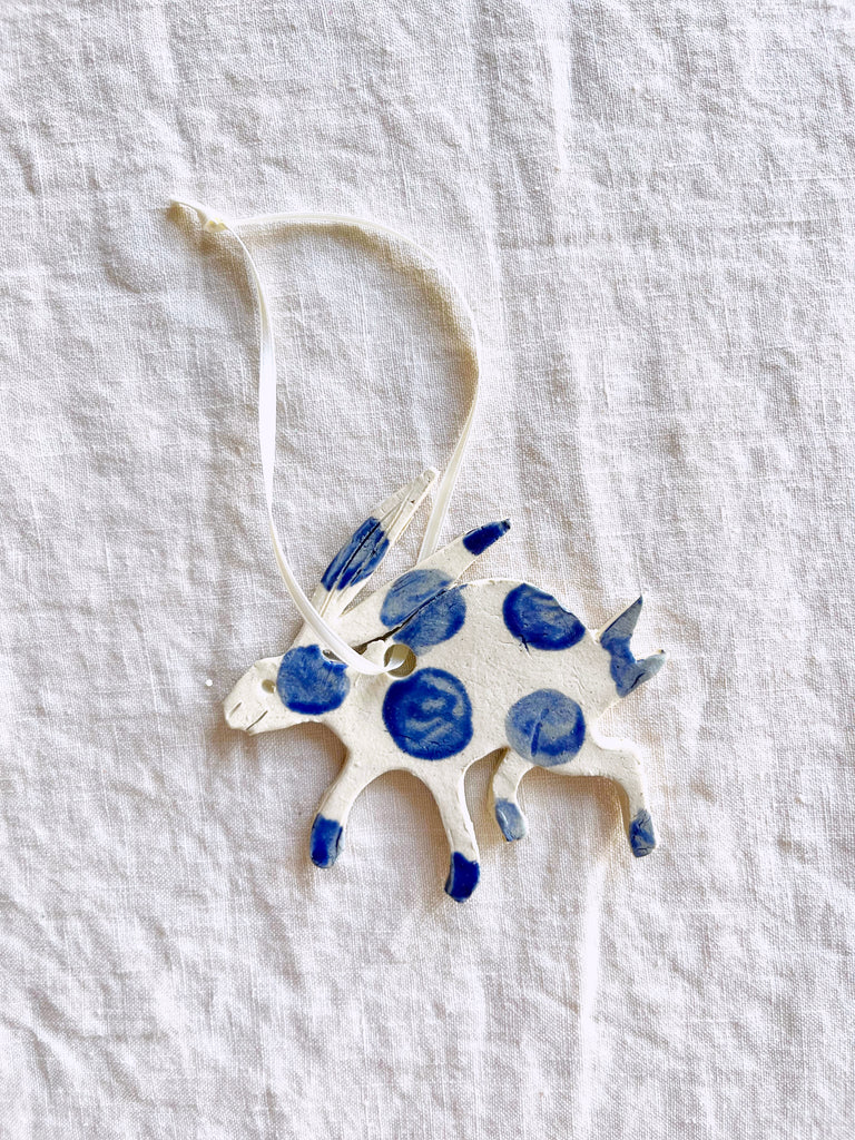 blue and white hand painted christmas ornament in shape of rabbit on white linen