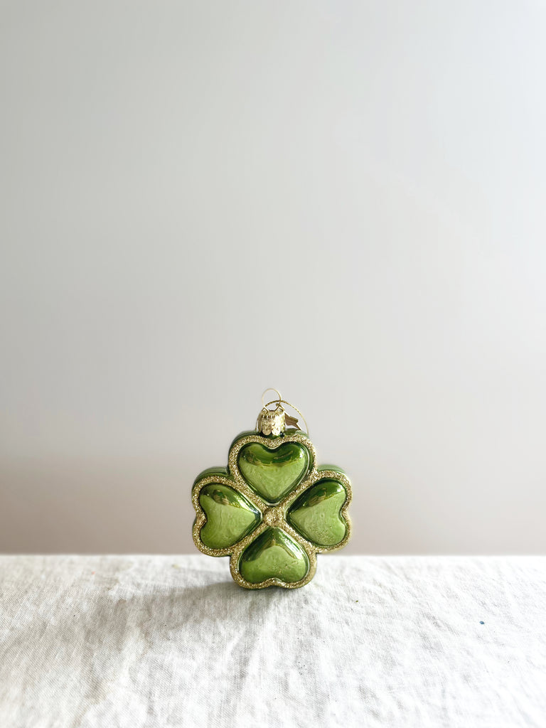 green four leaf clover glass christmas ornament on white table