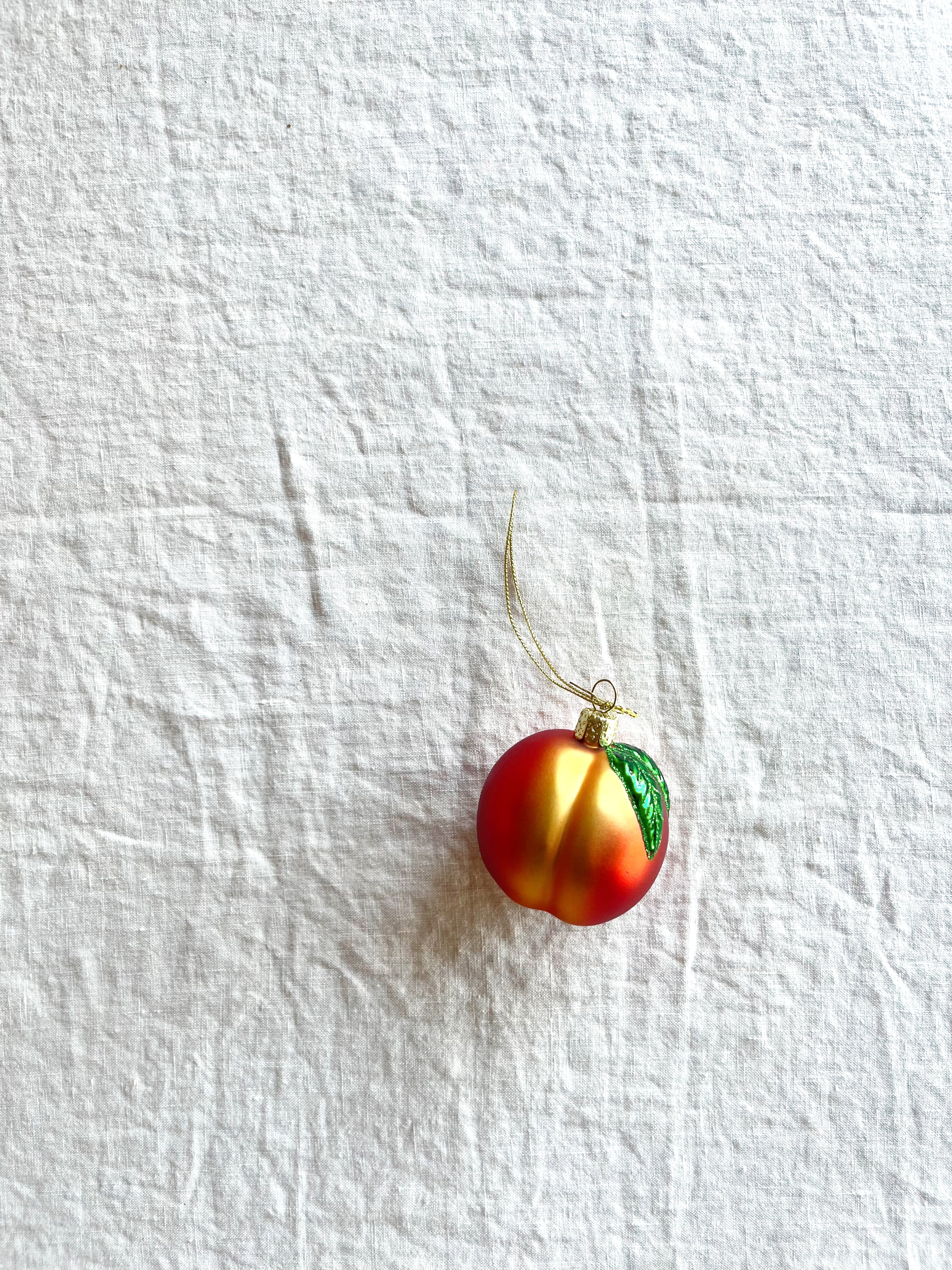 peach shaped glass christmas ornament on white table