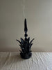 navy blue taper candle holder shaped like the top of a pineapple with candle