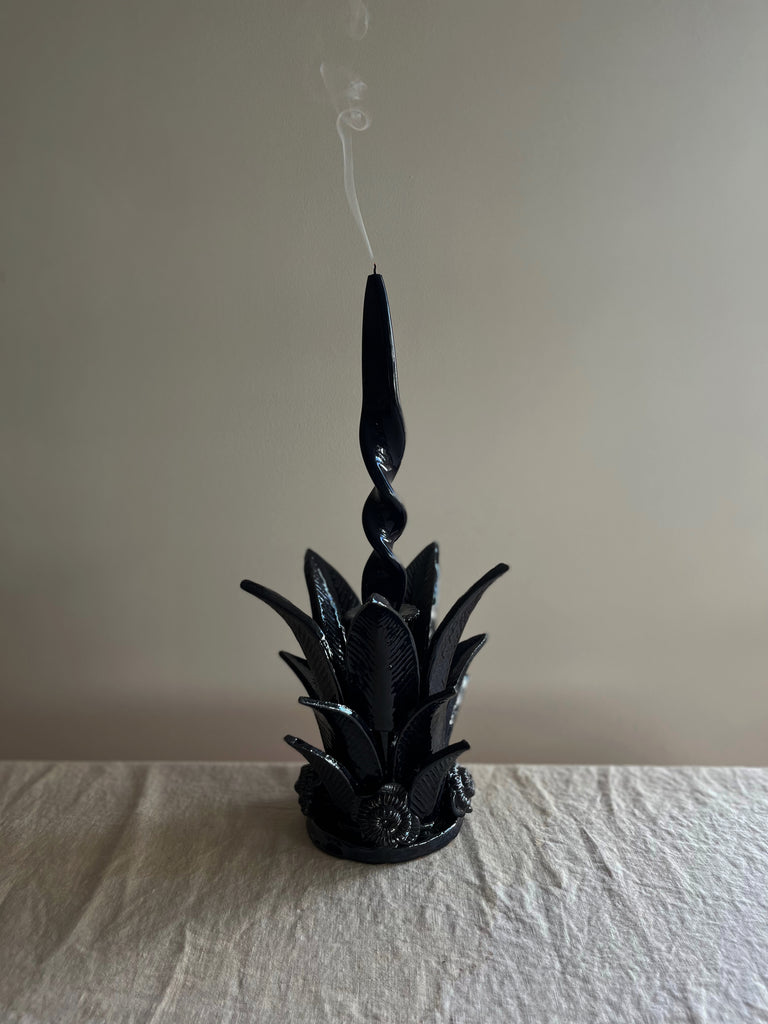 navy blue taper candle holder shaped like the top of a pineapple with candle
