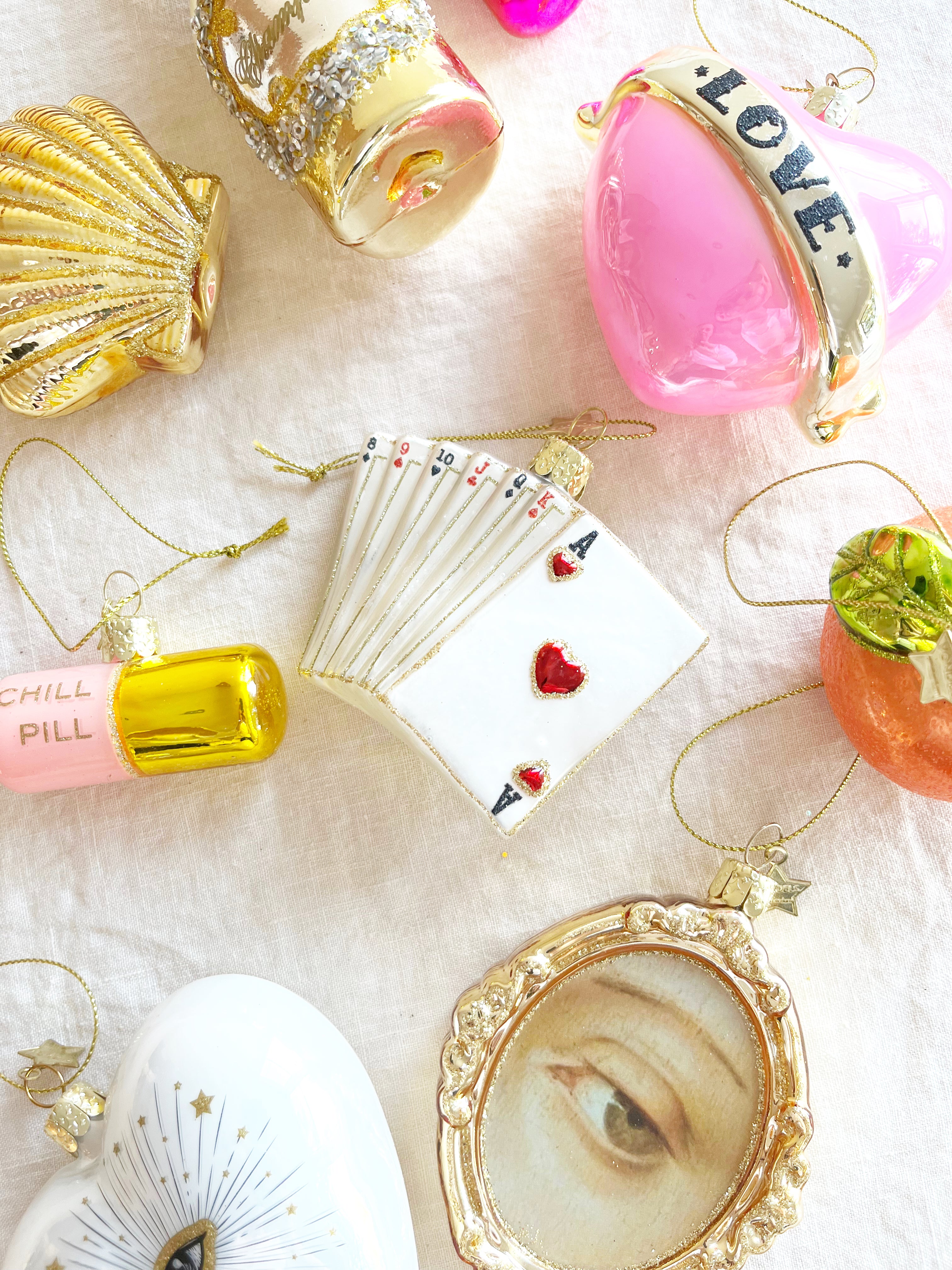 glass christmas ornament shaped like playing cards on table with other ornaments