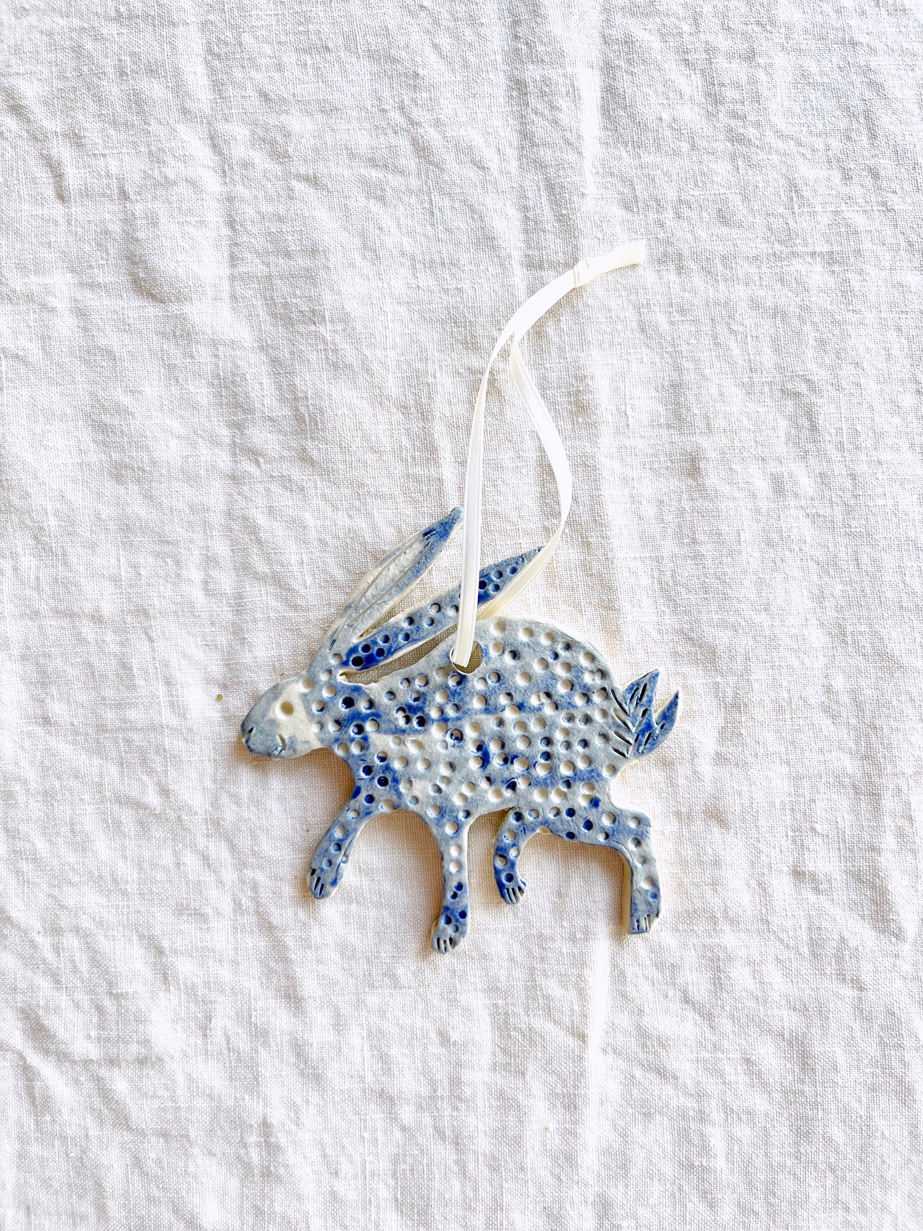 blue and white hand painted christmas ornament in shape of rabbit with white ribbon