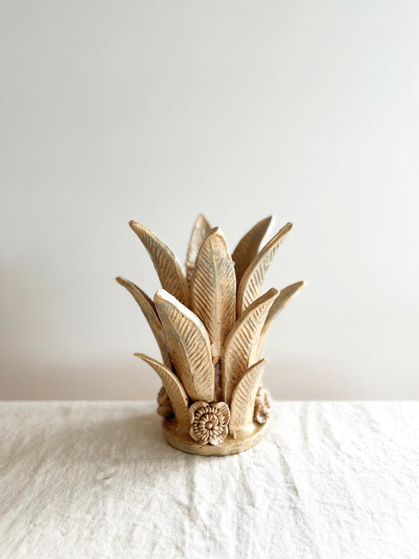 light brown taper candle holder shaped like the top of a pineapple