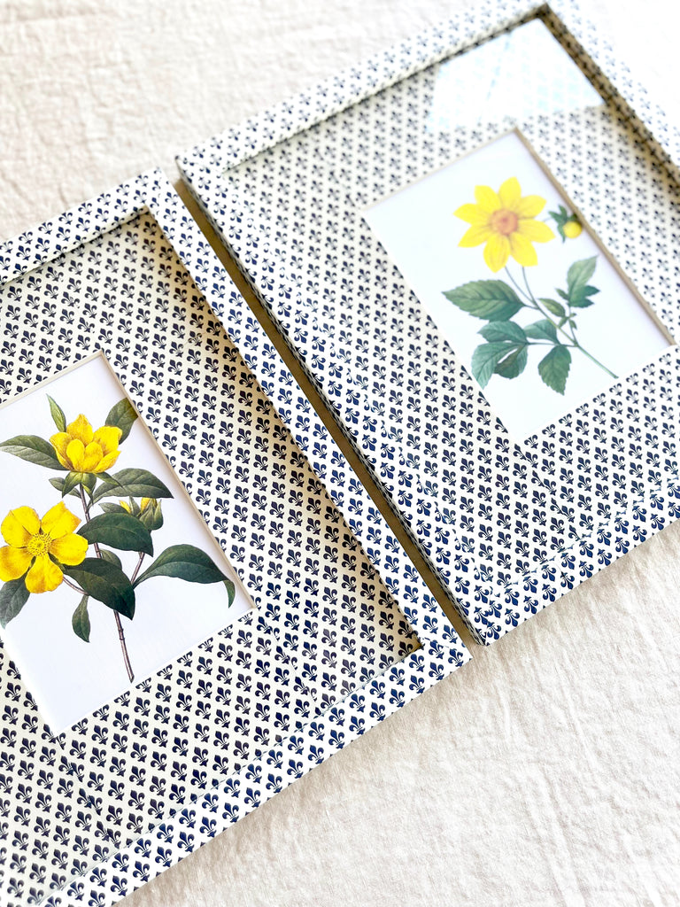 navy and white fleur de lys print paper wrapped frame and mat with yellow daisy botanical print 11" by 13" on white table