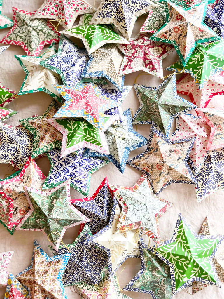 star shaped paper christmas ornaments shown in all colors
