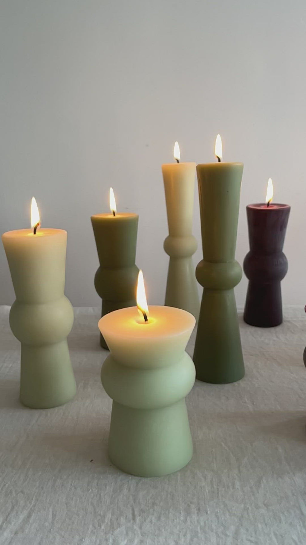 video of assorted totem candles light green seaweed plum wine light pink with flame lit