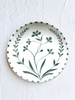 white porcelain dinner plate with green floral pattern on white table